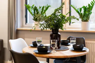 a table with glasses and a vase with flowers on it at Forest House by Cozyplace in Kraków