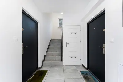 a hallway with two black doors and stairs at Forest House by Cozyplace in Kraków