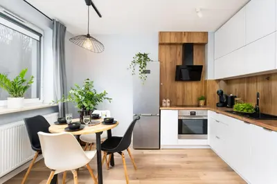 a kitchen with a table and chairs and a kitchen with white cabinets at Forest House by Cozyplace in Kraków