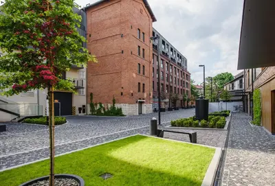 an empty street with a patch of grass next to a building at inQse Krakow Brewery Residence in Kraków