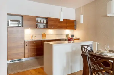 a kitchen with wooden cabinets and a table with chairs at BIG Prestige Apartment - 6 min Main Square Kraków in Kraków