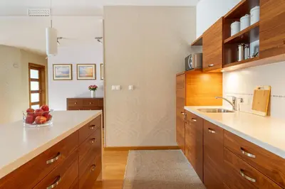 a kitchen with wooden cabinets and a bowl of fruit at BIG Prestige Apartment - 6 min Main Square Kraków in Kraków