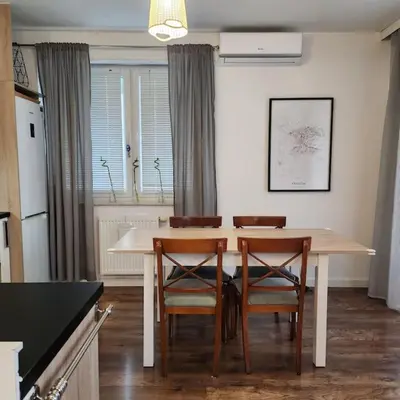 a kitchen with a table with chairs and a refrigerator at Korczaka Apartments Prokocim in Kraków