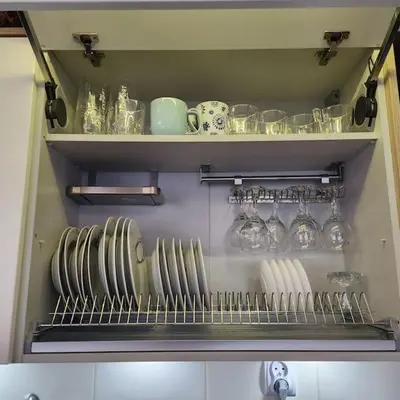 a kitchen with plates and glasses on a shelf at Korczaka Apartments Prokocim in Kraków
