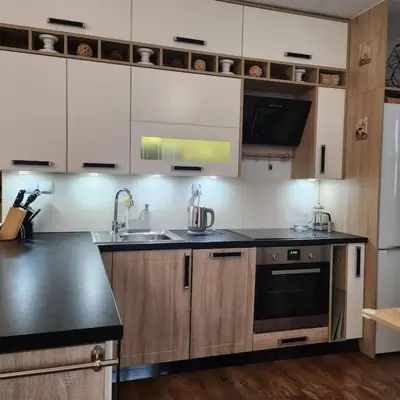 a kitchen with white cabinets and black counter tops at Korczaka Apartments Prokocim in Kraków
