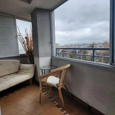 a balcony with a couch and a chair and a window at Korczaka Apartments Prokocim in Kraków