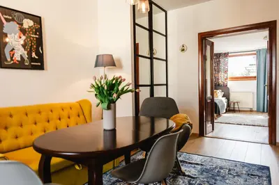 a living room with a table and a yellow couch at Vilao Apartments- Łazarza in Kraków