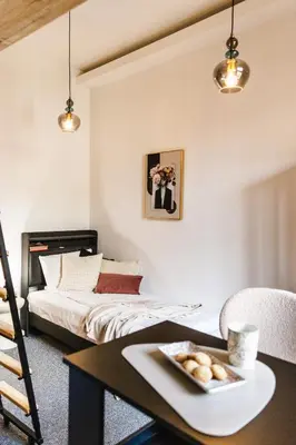 a bedroom with a bed and a table with a plate of bread at Vilao Apartments- Łazarza in Kraków