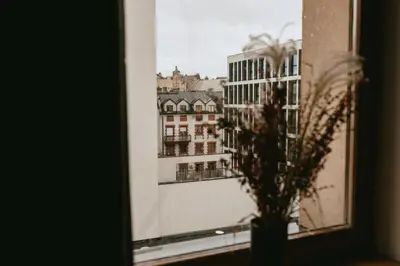 a window with a vase with a view of a building at Vilao Apartments- Łazarza in Kraków