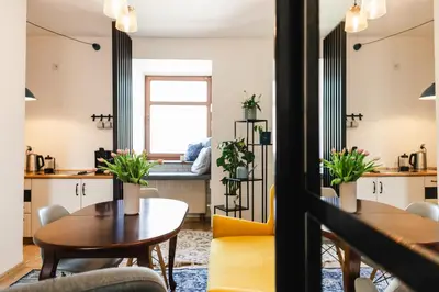 a living room with tables and chairs and a window at Vilao Apartments- Łazarza in Kraków