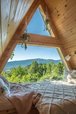 a bed in a room with a large window at Alemiło mini - domek z balią i widokiem na Babią Górę in Zawoja