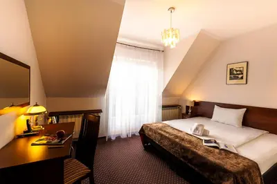 a hotel room with a bed and a desk and a window at Hotel Kasztelan in Dobczyce