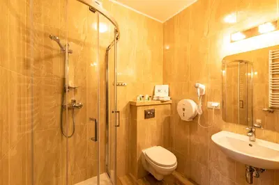 a bathroom with a shower and a toilet and a sink at Hotel Kasztelan in Dobczyce