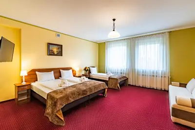 a hotel room with two beds and a couch at Hotel Kasztelan in Dobczyce