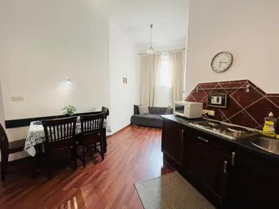a kitchen and living room with a table and a clock at Old Town Apartments 2 in Kraków