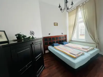 a bedroom with a bed with a dresser and a window at Old Town Apartments 2 in Kraków