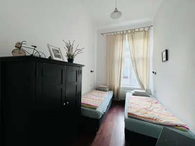 a room with two beds and a cabinet and a window at Old Town Apartments 2 in Kraków