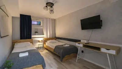 a bedroom with two beds and a flat screen tv at Przytulny Zakątek Wawel in Kraków