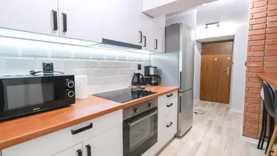 a kitchen with white cabinets and a brick wall at Przytulny Zakątek Wawel in Kraków