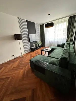 a living room with a green couch and wooden floors at Bajeczny Apartament 88 - 20 min to Cracow Airport - beside the Vistula River in Kraków