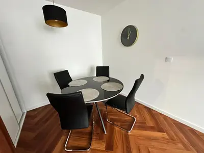 a dining room with a table and chairs and a clock at Bajeczny Apartament 88 - 20 min to Cracow Airport - beside the Vistula River in Kraków