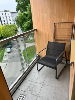 a chair on a balcony with a view of a street at Bajeczny Apartament 88 - 20 min to Cracow Airport - beside the Vistula River in Kraków