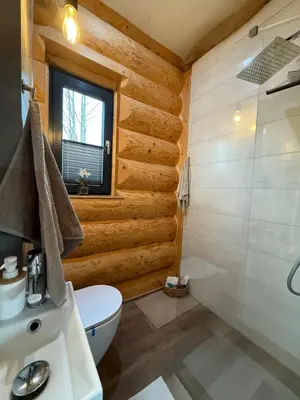 a bathroom with wooden walls and a toilet and a shower at Domek z Bali in Zawoja