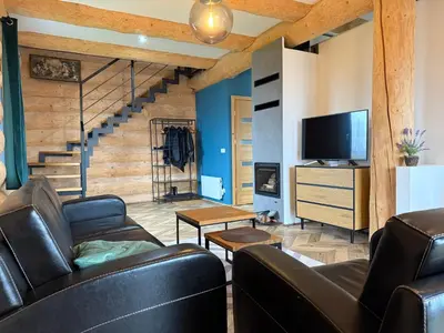 a living room with a couch and a tv and stairs at Domek z Bali in Zawoja