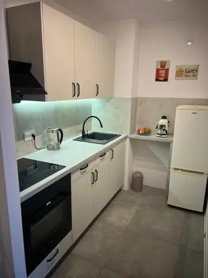 a kitchen with white cabinets and a sink and a refrigerator at Raciborska Loft in Kraków