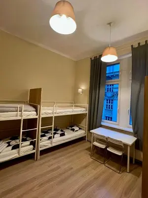 a room with two bunk beds and a table and a window at Fox hostel in Kraków