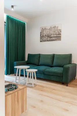 a living room with a green couch and two tables at K&M Apartments Tauron Arena in Kraków