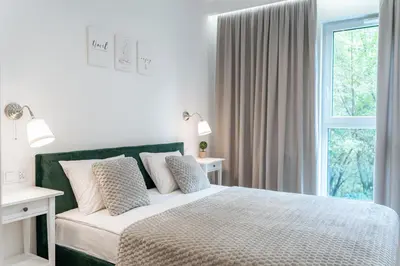 a white bedroom with a bed and a window at K&M Apartments Tauron Arena in Kraków