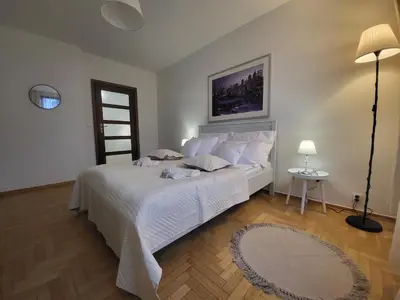 a bedroom with a white bed and a table and a lamp at Kochanowskiego 12 in Kraków
