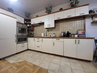 a kitchen with white cabinets and a tile wall at Kochanowskiego 12 in Kraków