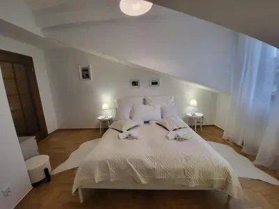 a white bedroom with a large bed with two lamps at Kochanowskiego 12 in Kraków