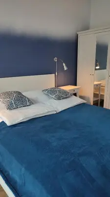a bed with a blue blanket and a lamp on it at Art Zwierzyniecka in Kraków