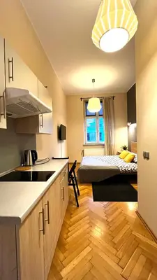 a kitchen with a room with a bed in the background at Studio in City Center in Kraków