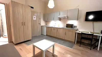 a kitchen with wooden cabinets and a table and a tv at Przestronne Studio w centrum in Kraków