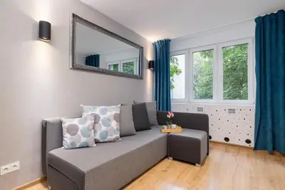 a living room with a couch and a mirror at Jasny Apartament blisko TAURON Arena Kraków by Noclegi Renters in Kraków