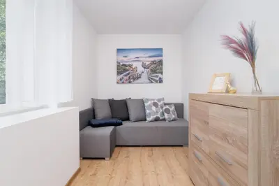 a living room with a couch and a dresser at Jasny Apartament blisko TAURON Arena Kraków by Noclegi Renters in Kraków