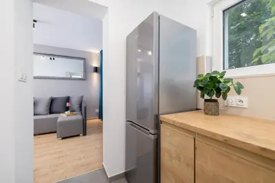 a kitchen with a stainless steel refrigerator next to a window at Jasny Apartament blisko TAURON Arena Kraków by Noclegi Renters in Kraków