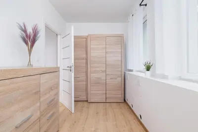 a bathroom with white walls and wooden drawers at Jasny Apartament blisko TAURON Arena Kraków by Noclegi Renters in Kraków