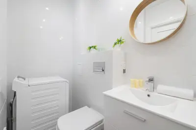 a white bathroom with a sink and a mirror at Jasny Apartament blisko TAURON Arena Kraków by Noclegi Renters in Kraków