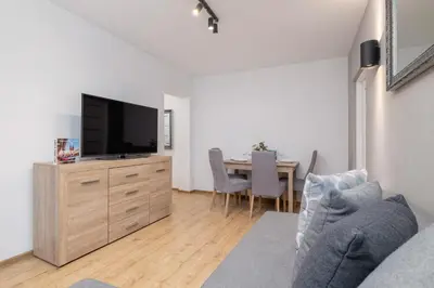 a living room with a couch and a tv and a table at Jasny Apartament blisko TAURON Arena Kraków by Noclegi Renters in Kraków
