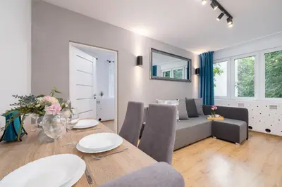 a living room with a table and a couch at Jasny Apartament blisko TAURON Arena Kraków by Noclegi Renters in Kraków