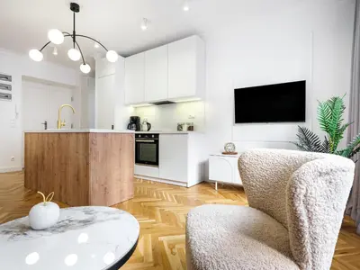 a kitchen with white cabinets and a chair and a table at Starowiślna by Tyzenhauz in Kraków