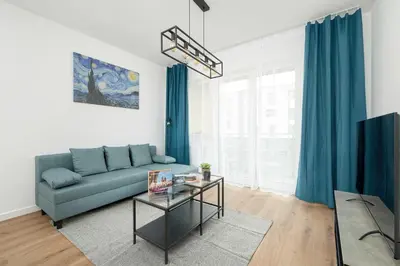 a living room with a blue couch and a glass table at Stylish Apartment near the Bonarka Shopping Center in Cracow by Noclegi Renters in Kraków