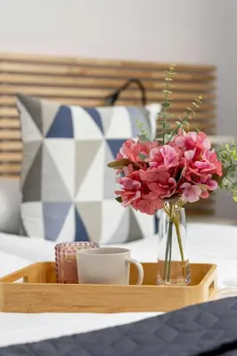 a wooden tray with a vase of flowers and a cup at Stylish Apartment near the Bonarka Shopping Center in Cracow by Noclegi Renters in Kraków