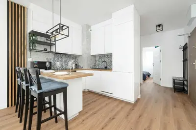 a kitchen with white cabinets and a table and chairs at Stylish Apartment near the Bonarka Shopping Center in Cracow by Noclegi Renters in Kraków