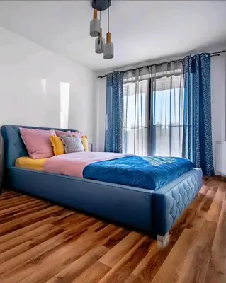 a blue bed in a room with a large window at Apartament N89 Wiślane Tarasy in Kraków